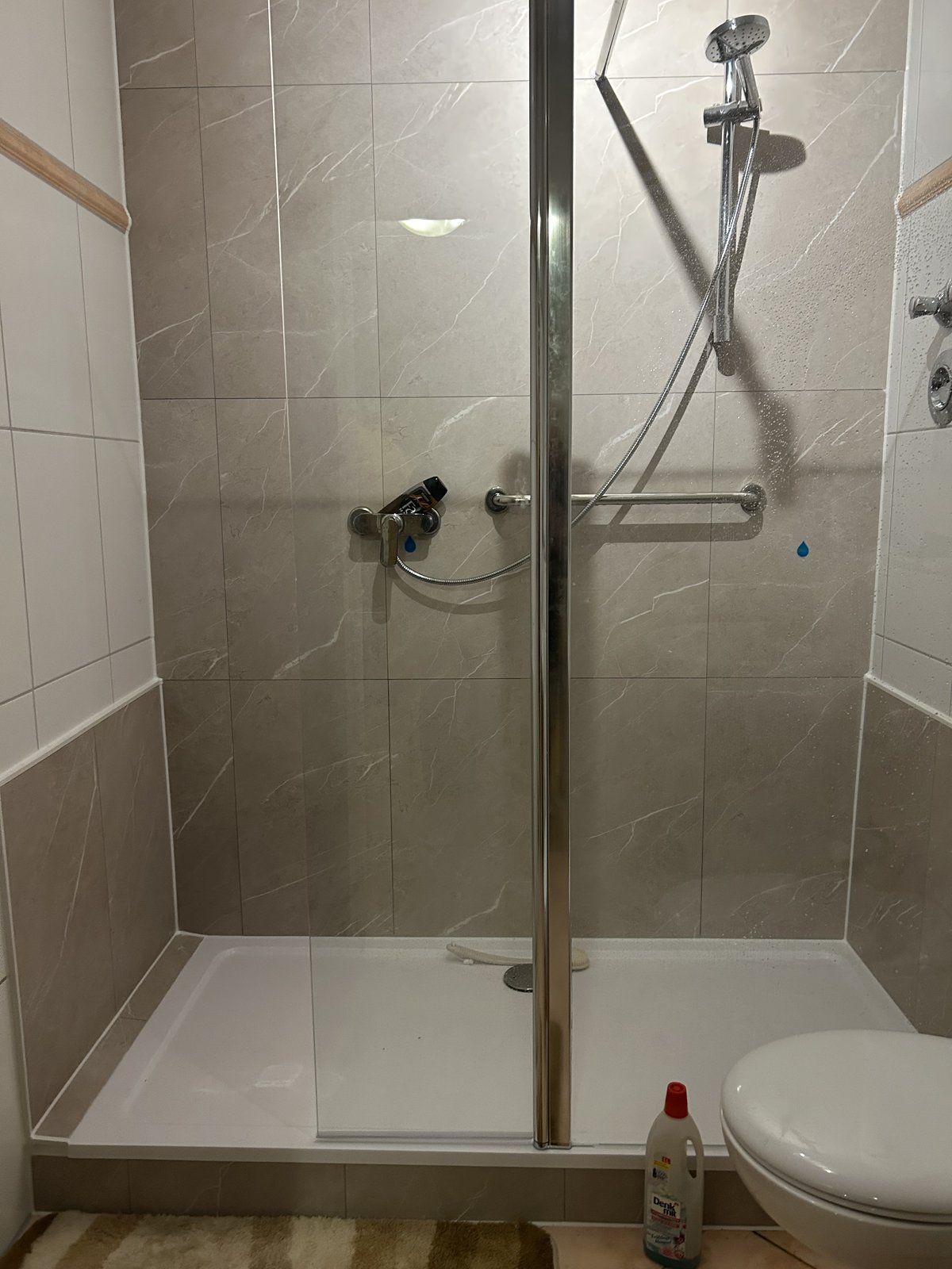 Nachher: Dusche mit Glastür, Haltegriff und hellen Wandpaneelen