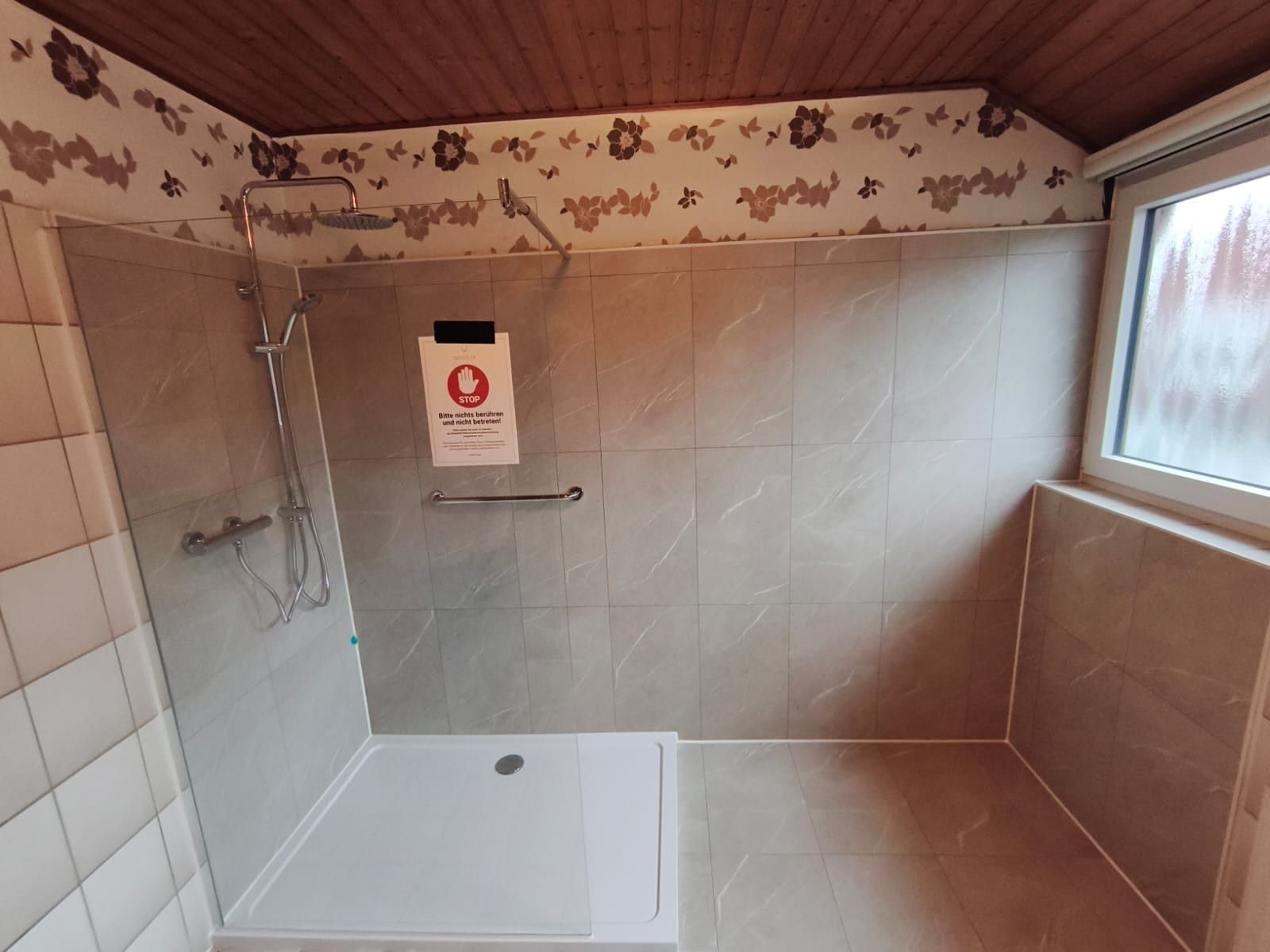 Nachher: große, flache Dusche mit Glaswand und Haltegriff unter der Dachschräge