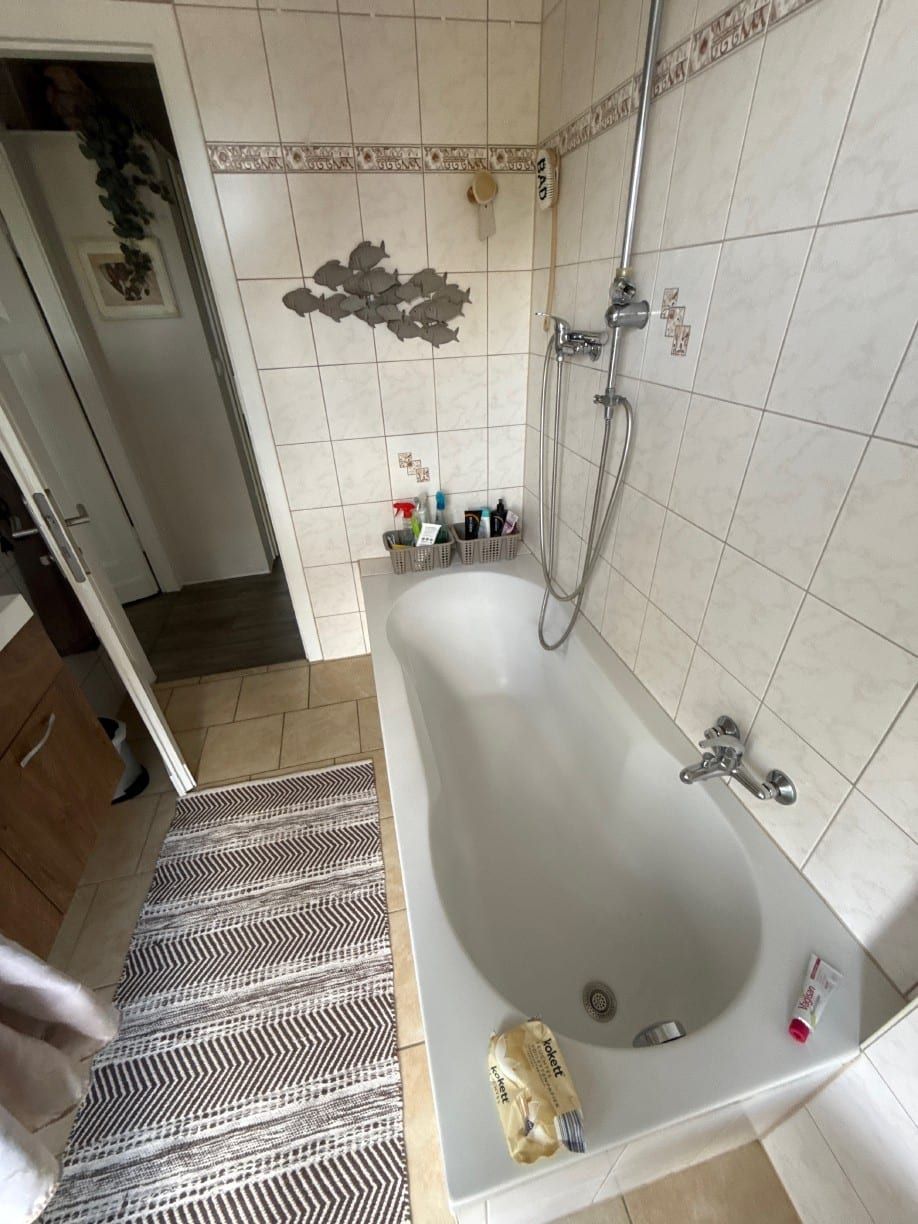 Vorher: Badewanne mit Brausestange, Fliesen mit Fisch-Dekor