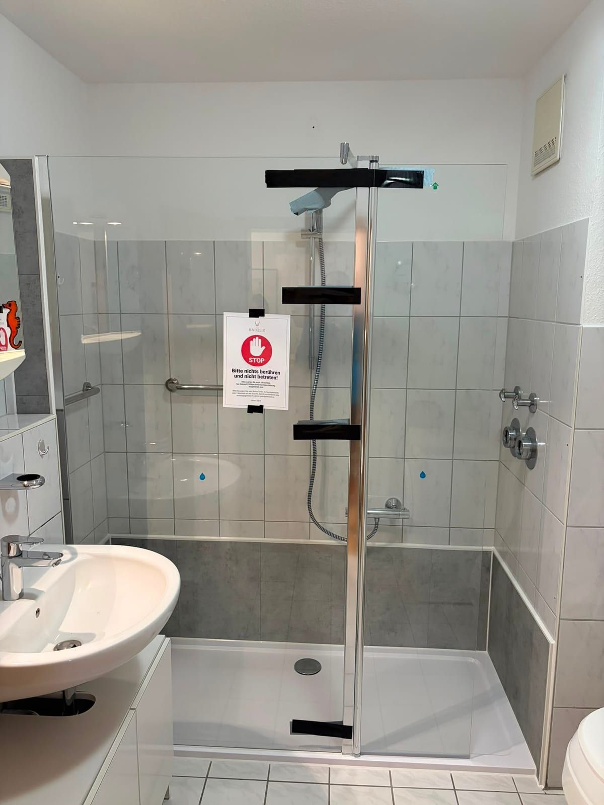 Nachher: bodennahe Dusche mit Glastür und hellen Wandpaneelen
