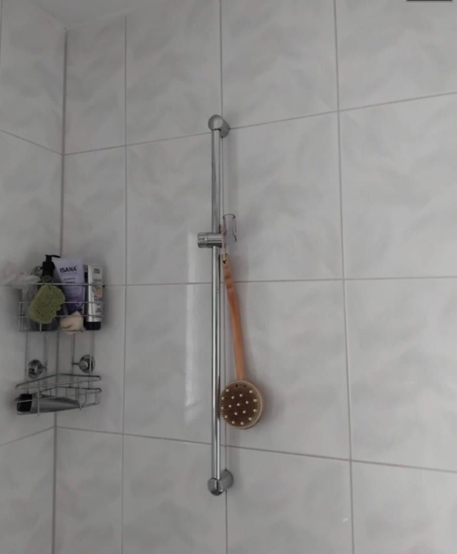 Vorher: Wand über der alten Wanne mit Brausestange