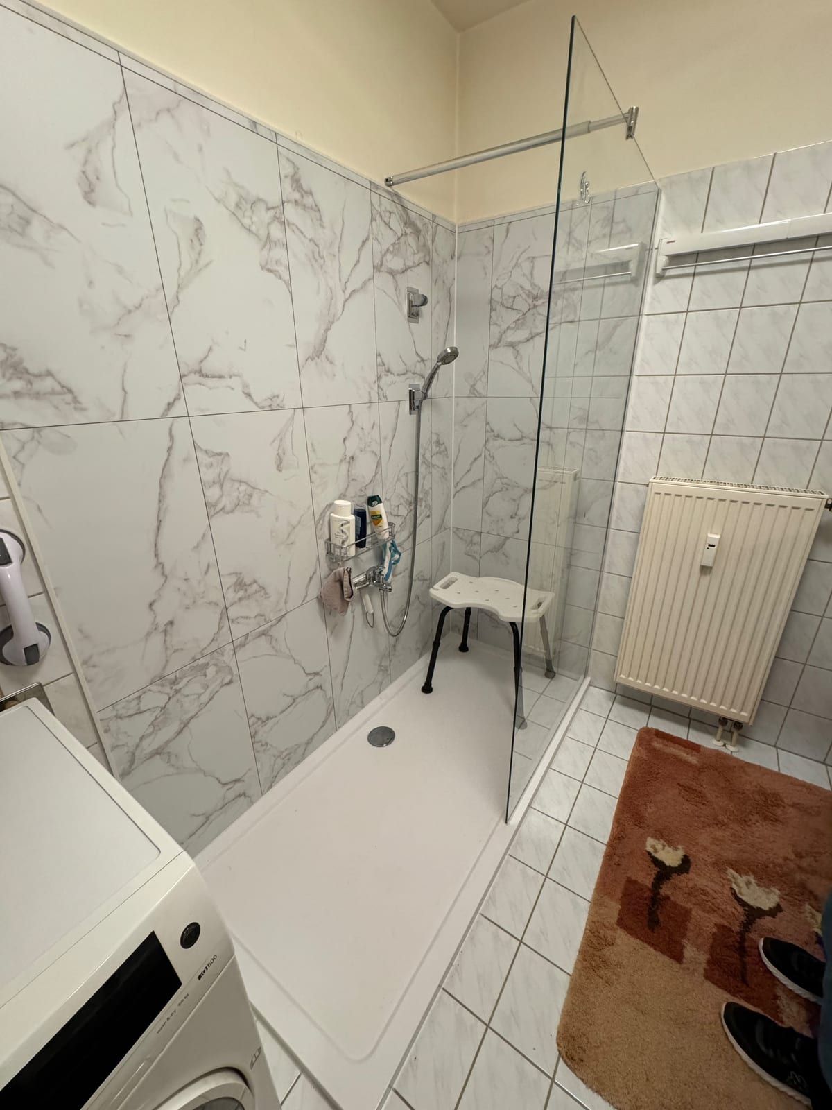 Nachher: Dusche mit Festglas, Wandpaneelen in Marmoroptik und Duschhocker