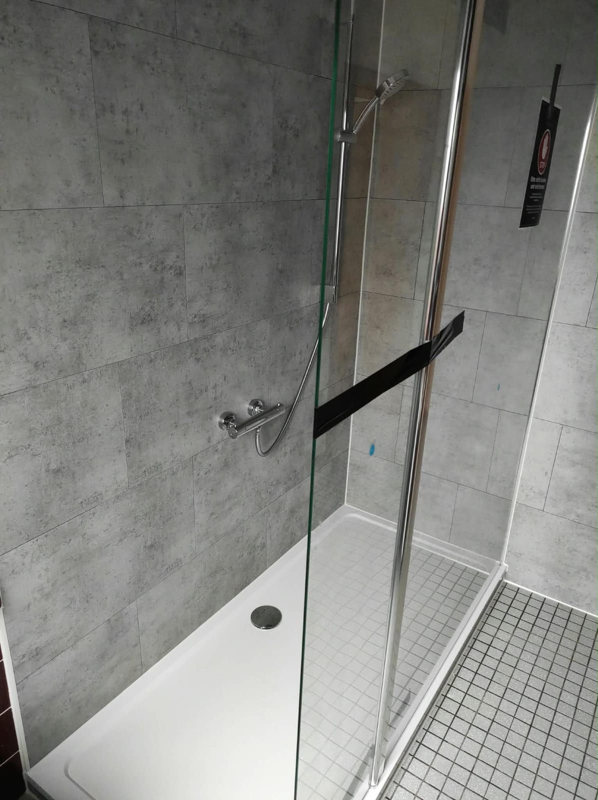 Nachher: Dusche mit Glaswand und grauen Wandpaneelen in Betonoptik