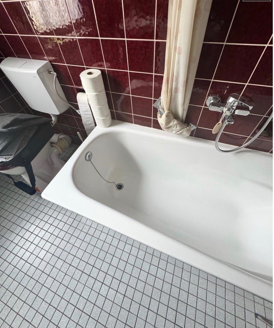 Vorher: Badewanne mit Duschvorhang, dunkelrote Wandfliesen