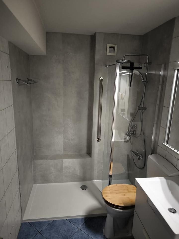 Nachher: Dusche mit Haltegriff und hellen Wandpaneelen