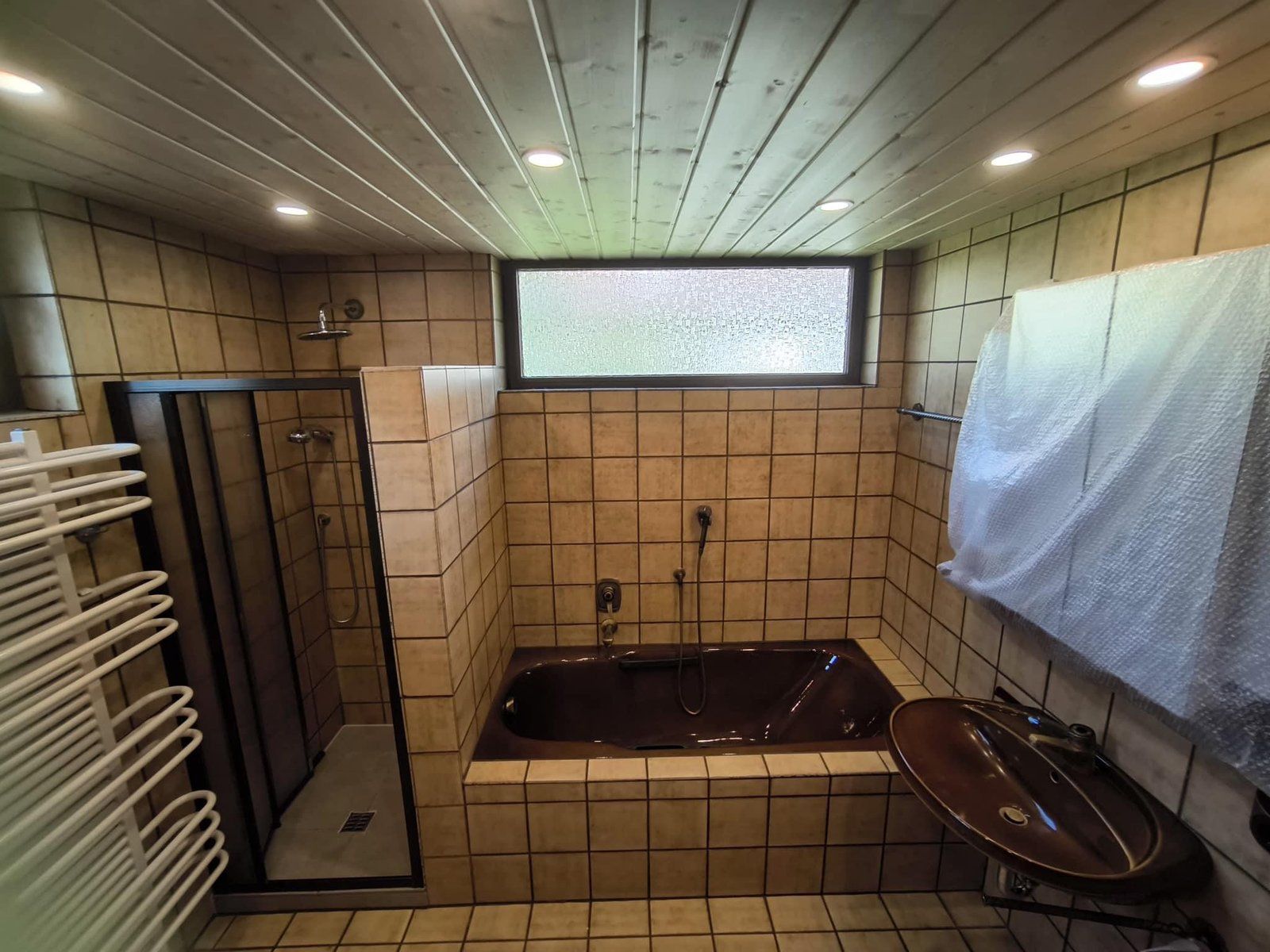 Vorher: braune Badewanne, beige Fliesen, Holzdecke