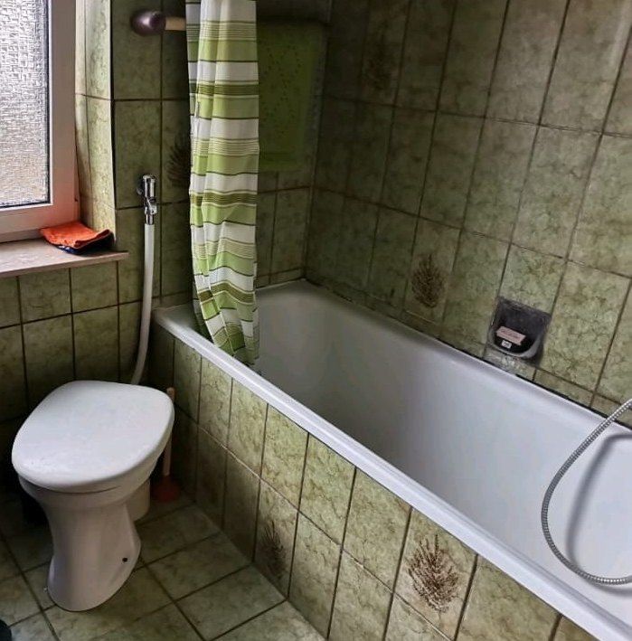 Vorher: Badewanne mit Duschvorhang, grüne Fliesen