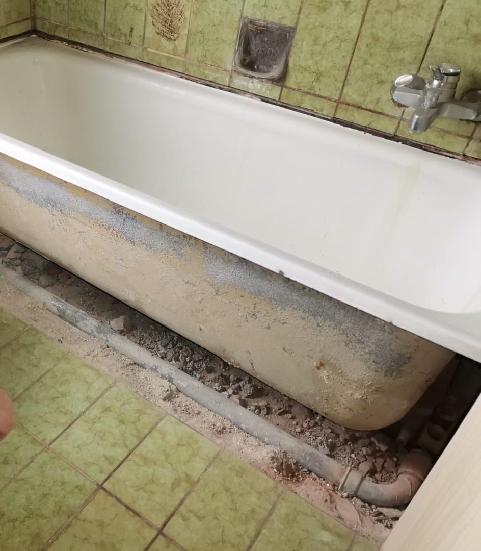 Die Badewanne ist freigelegt, darunter Rohre und Bauschutt
